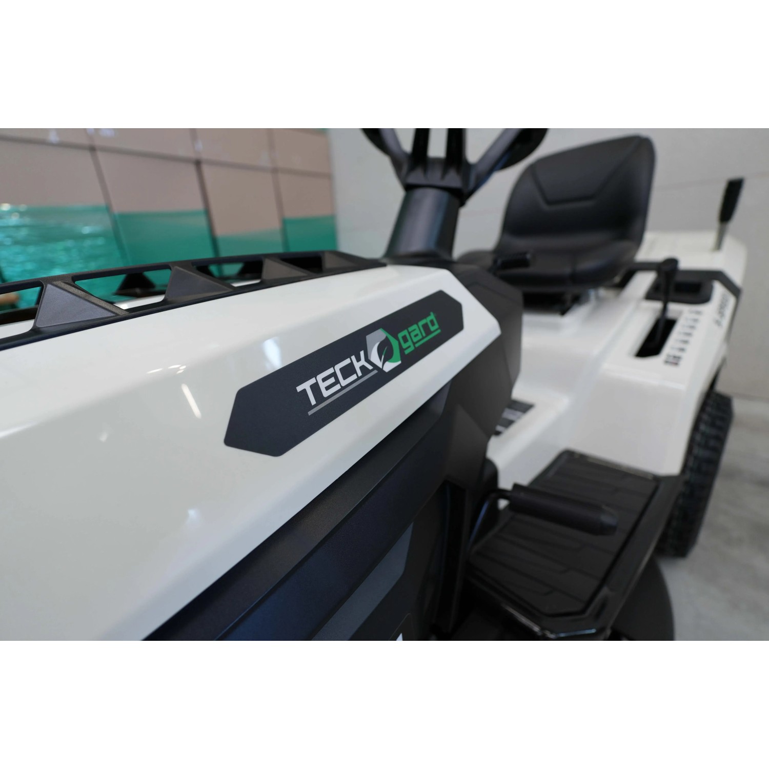 Trattorino tagliaerba Teckgard bianco, vista dettagliata del logo e dei comandi.