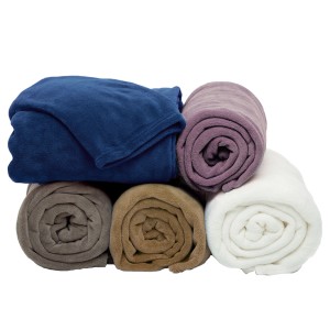 Coperte e plaid arrotolati in vari colori.