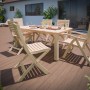 Scena da giardino con sedia pieghevole Canston in legno naturale e tavolo da giardino abbinato su una terrazza.