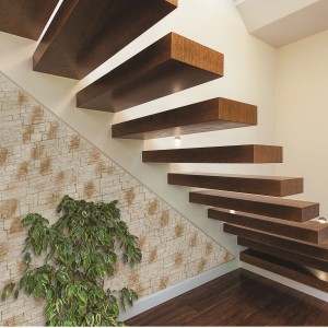 Rivestimento murale effetto pietra accanto a una scala con elementi in legno e una pianta.