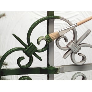 Pennello per ritocchi LUX misura 0 mentre dipinge una recinzione metallica.