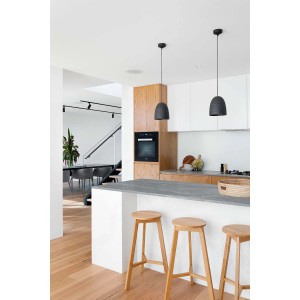 Cucina moderna con due lampade a sospensione nere sopra un'isola con sgabelli.