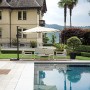 Elegante ombrellone a braccio che ombreggia un salotto a bordo piscina.