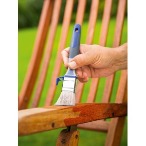 Mano che tinge il legno con pennello piatto LUX 30 mm. Pennello con serbatoio per impregnante.