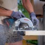 La sega circolare a batteria Bosch Professional GKS 18 V-57 G in azione mentre taglia il legno.