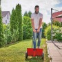 Spargitore Einhell GC-SR 12 in uso: uomo spinge spargitore di fertilizzante rosso su prato in giardino.