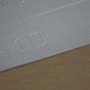 Dettaglio di uno zerbino/tappeto da cucina t.b.t. con motivo a rombi e il numero 10.