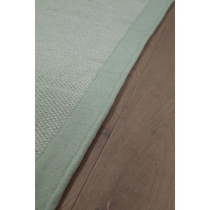 Dettaglio di una stuoia t.b.t. Stuoie verde chiaro su pavimento in legno.