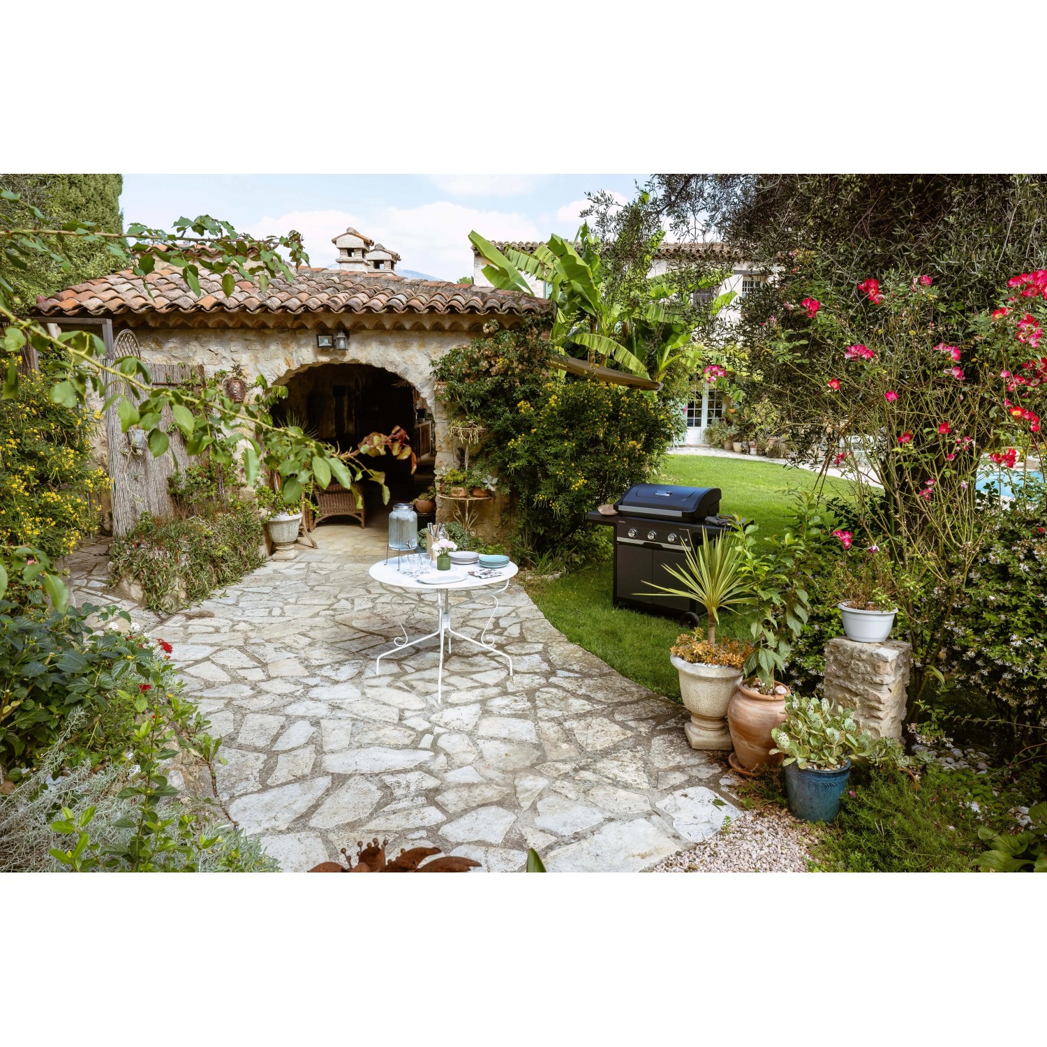 Barbecue a gas t.b.t. in giardino con tavolo e piante.