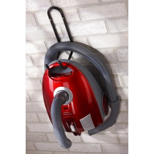 Aspirapolvere rosso con tubo flessibile su un supporto a parete su un muro di mattoni.