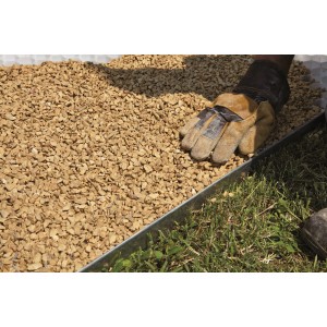 Primo piano di t.b.t. ghiaia decorativa/pietrisco con guanto e prato in giardino.