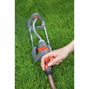 Irrigatore da giardino con raccordo per l'acqua in uso su prato.