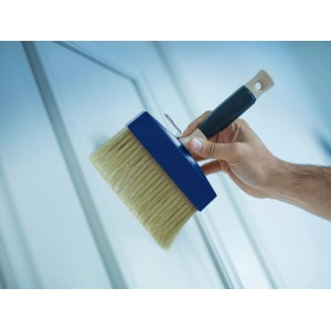 Pennello largo con testa blu e manico in legno in mano.