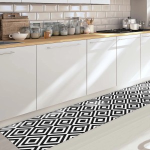 Tappeto da cucina nero con motivo geometrico davanti a mobili da cucina bianchi.