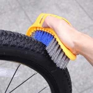 Spazzola gialla per bici con setole blu e grigie che pulisce un pneumatico.