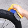 Spazzola gialla per bici con setole blu e grigie che pulisce un pneumatico.