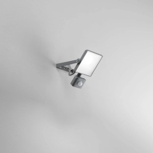 Faro da cantiere LED t.b.t. grigio con sensore di movimento montato a parete.