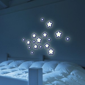 Stelle luminose come adesivi da parete sopra un letto. Adesivi murali decorativi per camerette.