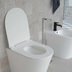 WC bianco t.b.t. con coperchio aperto, bidet e rubinetto in bagno.