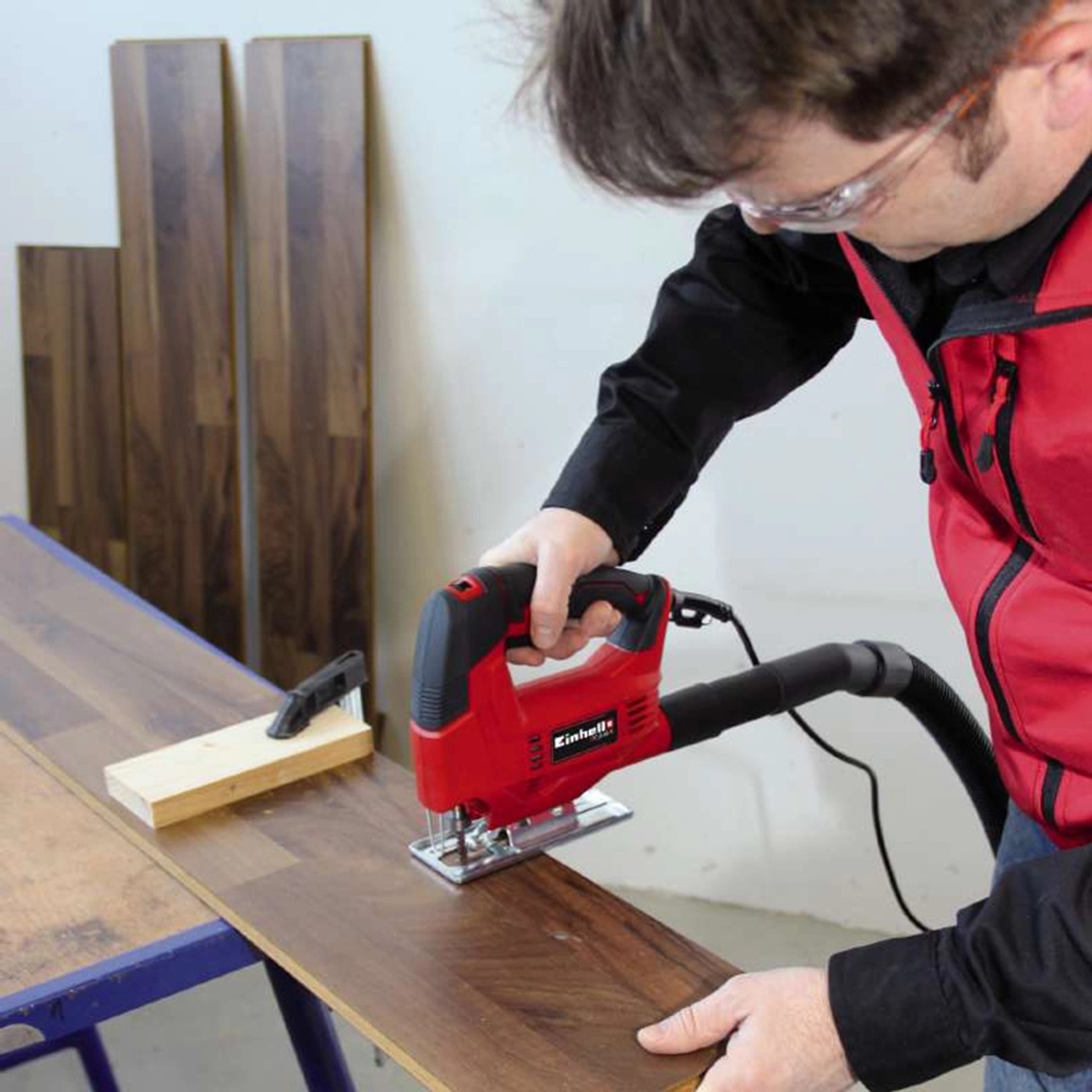 Seghetto alternativo Einhell TC-JS 60/1 in uso per tagliare il legno. Seghetto alternativo rosso con aspirazione polvere.