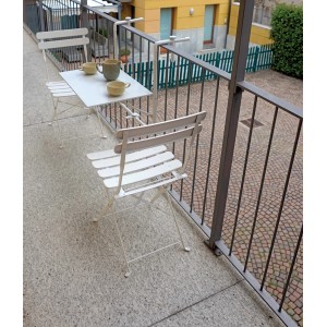 Set mobili da balcone bianco: tavolo e due sedie su un balcone.