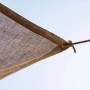 Dettaglio di una vela ombreggiante marrone (t.b.t.) con fissaggio a corda su cielo chiaro.