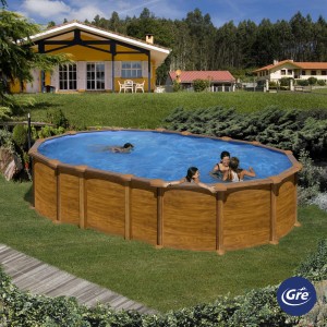 Piscina ovale Gre Amazonia effetto legno (610x375x132 cm) con persone che nuotano in giardino.