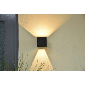 Applique da esterno t.b.t. nera quadrata su muro con effetti di luce.