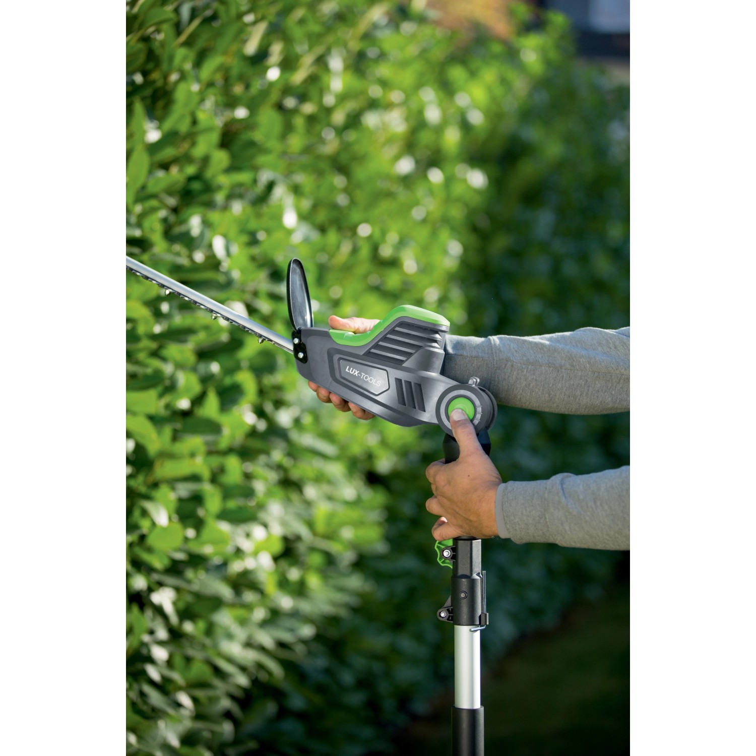 Tagliasiepi telescopico a batteria LUX A-HS-20/51T in uso per tagliare una siepe.