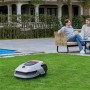 Robot rasaerba Dreame A1 Pro su prato davanti a casa con piscina e persone rilassate.