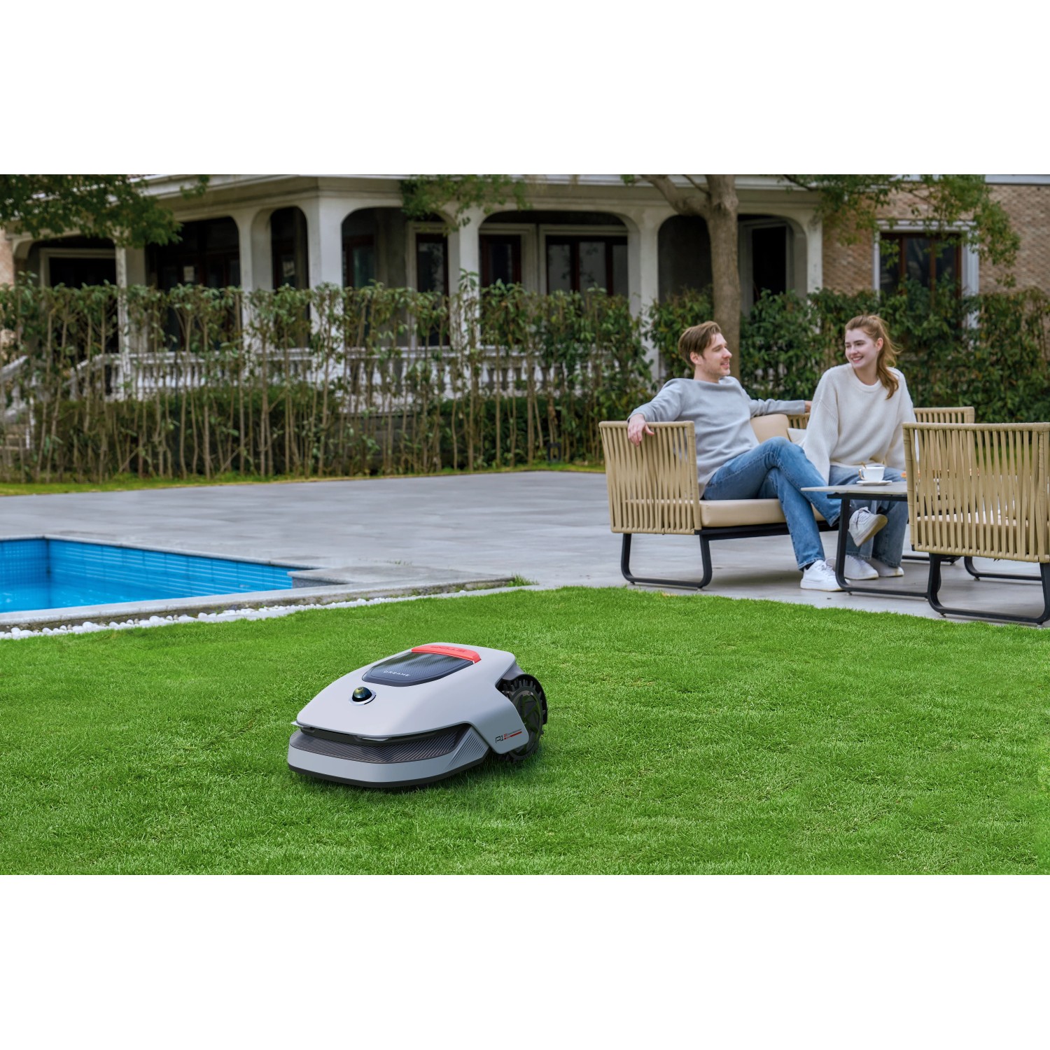 Robot rasaerba Dreame A1 Pro su prato davanti a casa con piscina e persone rilassate.