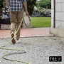 Uomo con tubo per irrigazione t.b.t. in giardino.