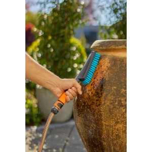 Gardena Cleansystem Spazzola a mano Hard S con raccordo per tubo flessibile in uso su un vaso.