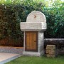 Fontana da giardino in pietra con porta in legno e rubinetto.