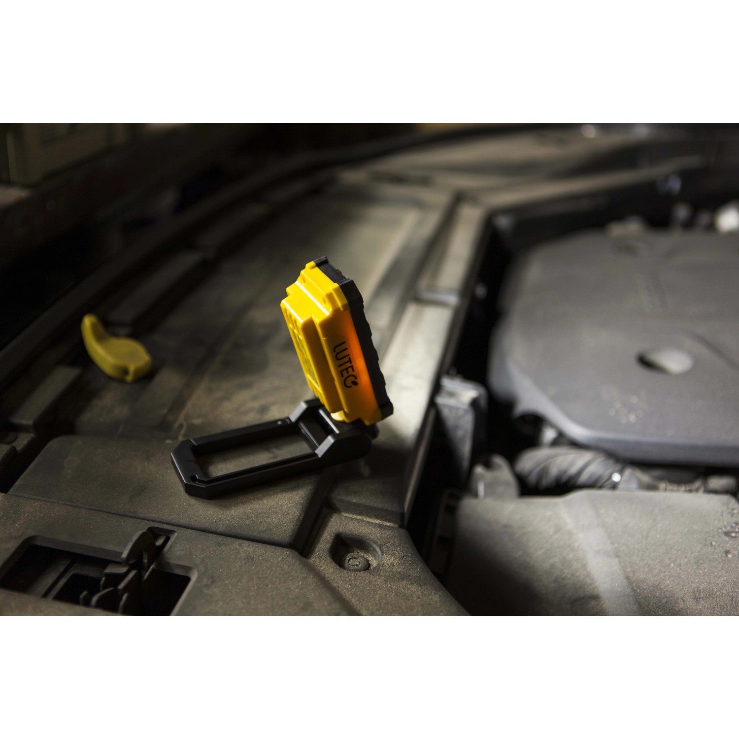 Luce da lavoro a LED t.b.t. gialla in uso sotto il cofano di un'auto.