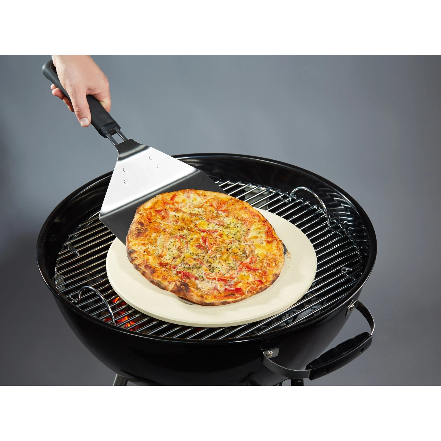 Paletta per pizza Jamestown con pizza sulla griglia. Sollevatore in acciaio inox per pizza croccante.