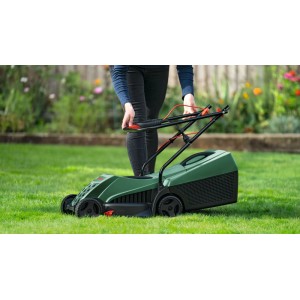 Persona taglia prato con tosaerba elettrico Bosch Easy Rotak 32-215 verde. Maniglie pieghevoli per facile uso in giardino.