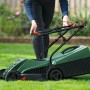 Persona taglia prato con tosaerba elettrico Bosch Easy Rotak 32-215 verde. Maniglie pieghevoli per facile uso in giardino.