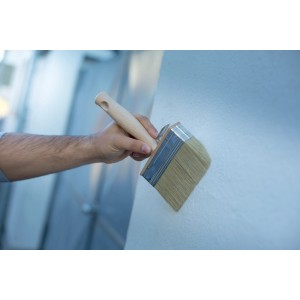 Mano che dipinge la parete con pennello LUX 14x4 cm. Dipingere è facile.