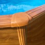 Dettaglio Gre Pool Sicilia Oval con effetto legno, piscina con pareti in acciaio ed elementi marroni.