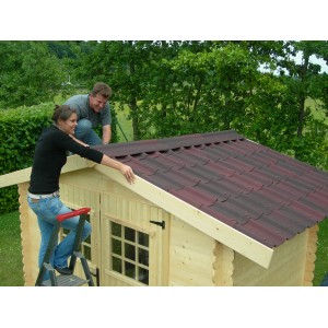 Installazione di una copertura bituminosa rossa su una casetta da giardino. Le membrane bituminose proteggono dalle intemperie.