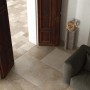 Piastrelle per esterno t.b.t. beige posate in un soggiorno con divano e porte in legno.
