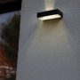 Lampada da parete solare a LED nera Lutec Fadi con sensore di movimento e luce bianca calda.
