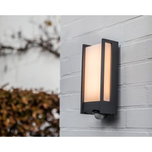 Moderna lampada da parete per esterni a LED Lutec Qubo con sensore di movimento su muro di mattoni bianchi.
