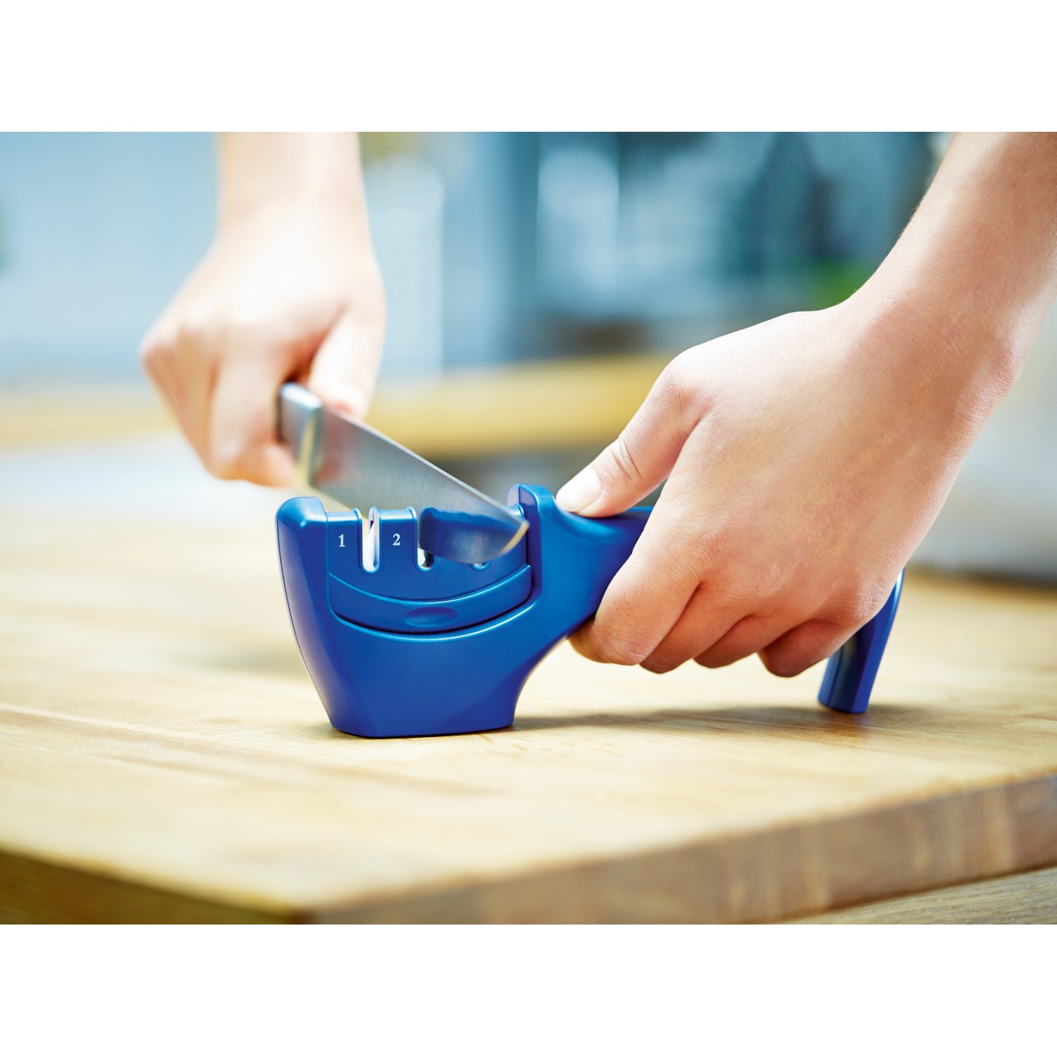 Affilacoltelli LUX in azione: coltello che viene fatto scorrere nell'affilacoltelli blu.