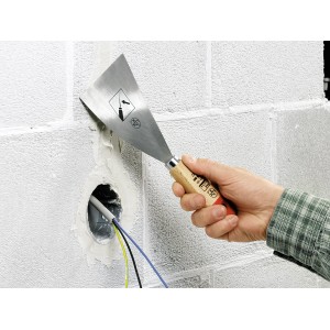 Mano che tiene spatola LUX rigida (100mm) per lisciare lo stucco su una parete.