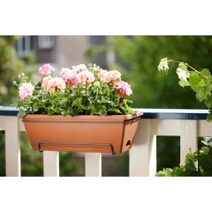 Fioriera marrone con supporto e gerani rosa su un balcone.