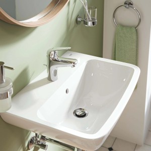 Lavabo t.b.t. con miscelatore monocomando cromato su sfondo verde chiaro.