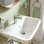 Lavabo t.b.t. con miscelatore monocomando cromato su sfondo verde chiaro.
