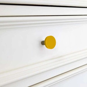 Pomello giallo su cassetto bianco. Design semplice per mobili e cassettiere.